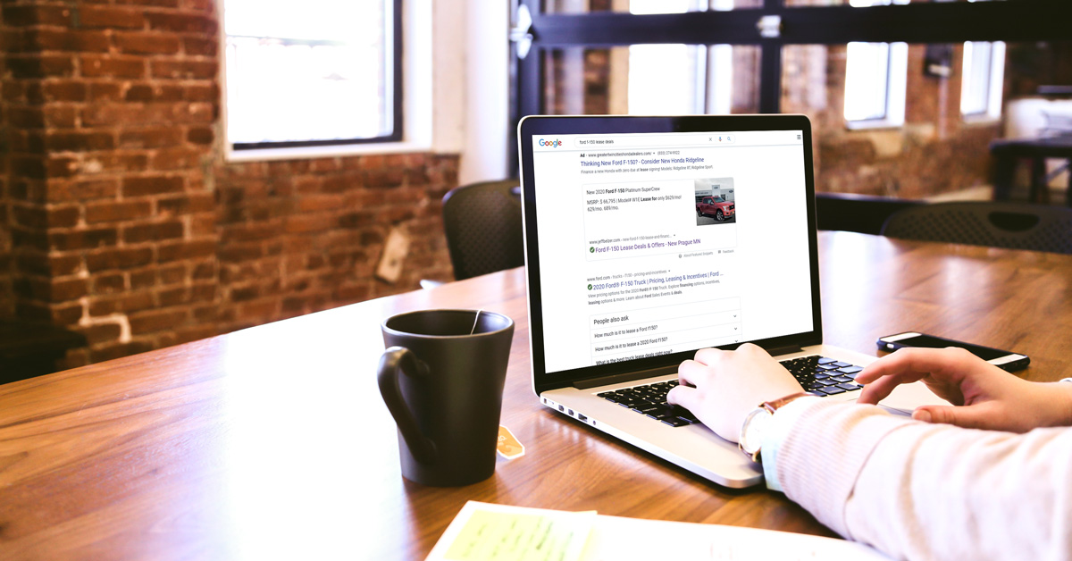 person searching google for ford f-150 deals on a laptop in a coffee shop