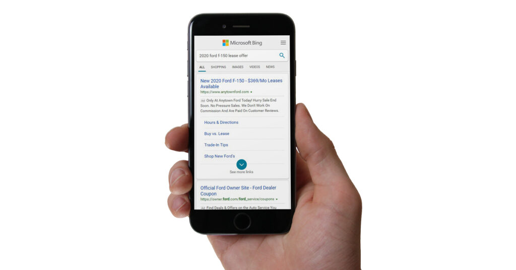 201125.1_-_Microsoft_Advertising_Dealer_Teamwork_phone_hand_1200x628 person holding mobile phone looking at a paid search ad on bing